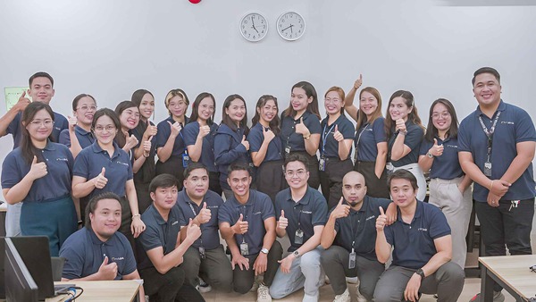 Approximate 25 Outdesk staff with thumbs up - all wearing blue polo shirts